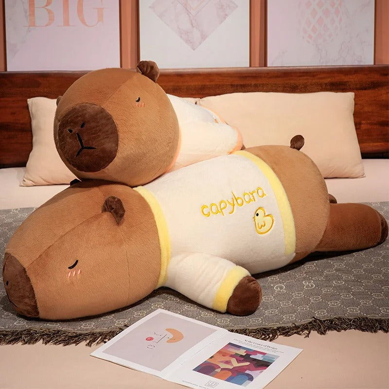 Giant capybara plush in yellow pajama outfit resting on bed, soft body pillow stuffed animal.