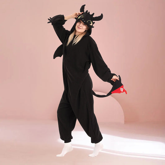 Black dragon kigurumi onesie featuring wings, tail, and detailed hood, modeled on a pink background. Perfect for kigurumi and dragon onesie enthusiasts.