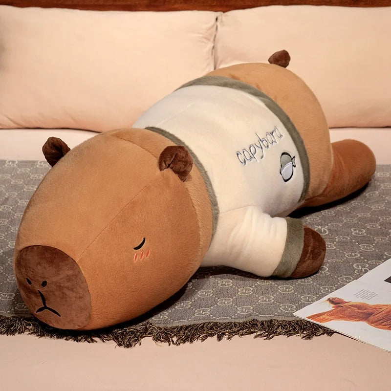 Oversized capybara plush toy in gray fish pajama outfit, cuddly stuffed animal pillow.