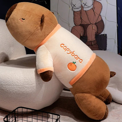 Two giant capybara plush stuffed animals wearing pajamas stacked together on the floor.